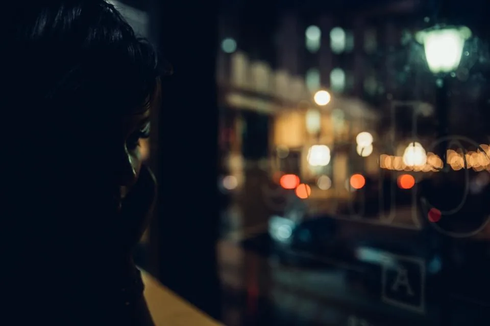 A young person silhouetted against city lights at night